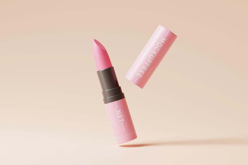 Close-up of hands holding various lip crayons with soft-focus background of makeup brushes and skincare products